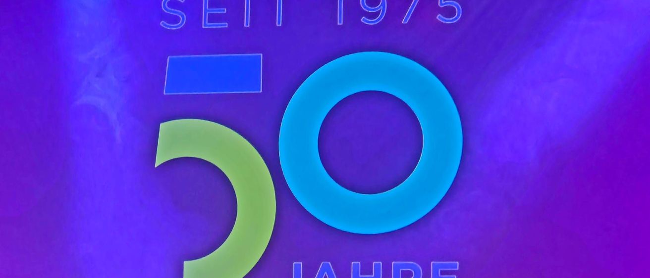Ein violetter Hintergrund mit einem blau-grünen Logo, das 'RDA EXPO SEIT 1975 50 JAHRE' besagt, was 50 Jahre seit 1975 bedeutet.