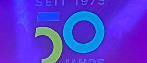 Ein violetter Hintergrund mit einem blau-grünen Logo, das 'RDA EXPO SEIT 1975 50 JAHRE' besagt, was 50 Jahre seit 1975 bedeutet.