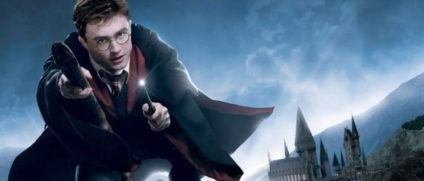 Ein Zauberer fliegt in der Luft und hält eine Zauberstange und einen Besen. Er trägt eine Schuluniform. Hinter ihm befindet sich ein Schloss auf einem Berg.