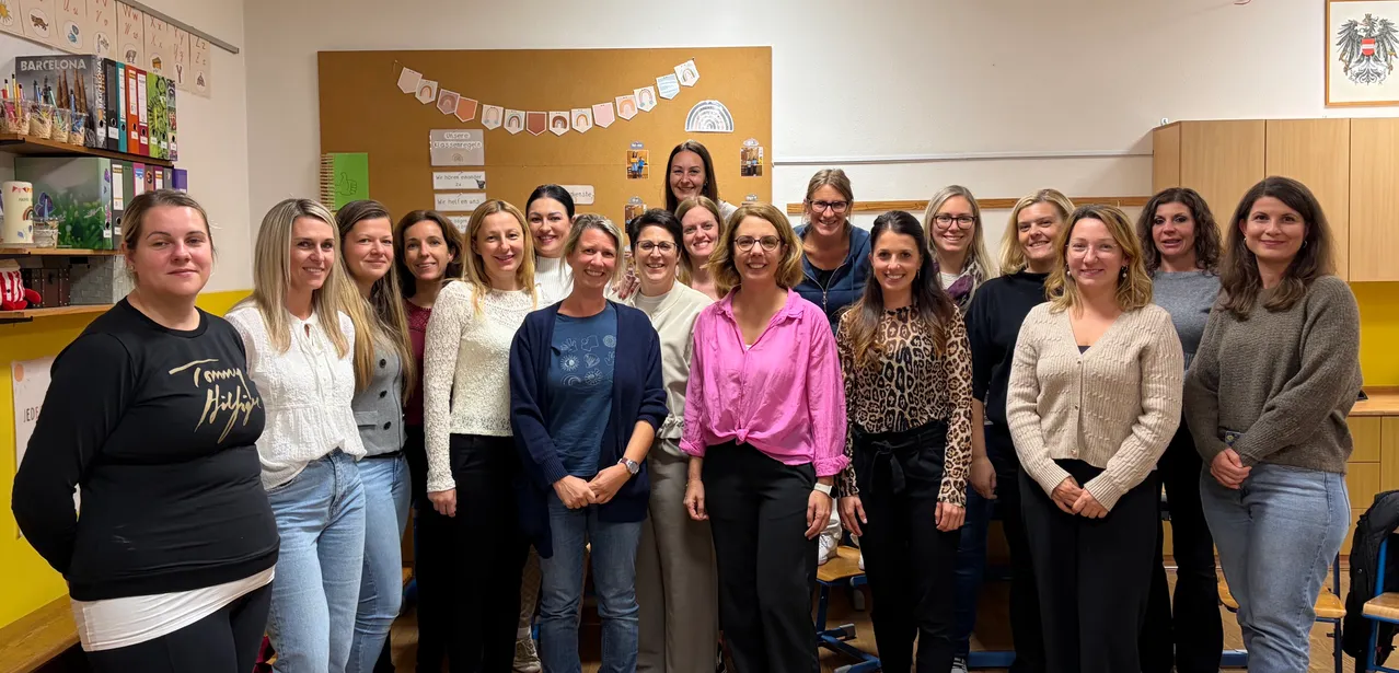 Eine Gruppe von Frauen in einem Klassenzimmer, lächelnd und für ein Foto posierend.