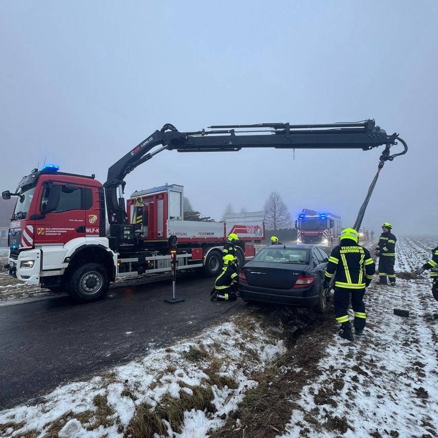 Ein Autounfall auf einer verschneiten Straße. Feuerwehrleute retten die Insassen des Autos mit einem Kran.