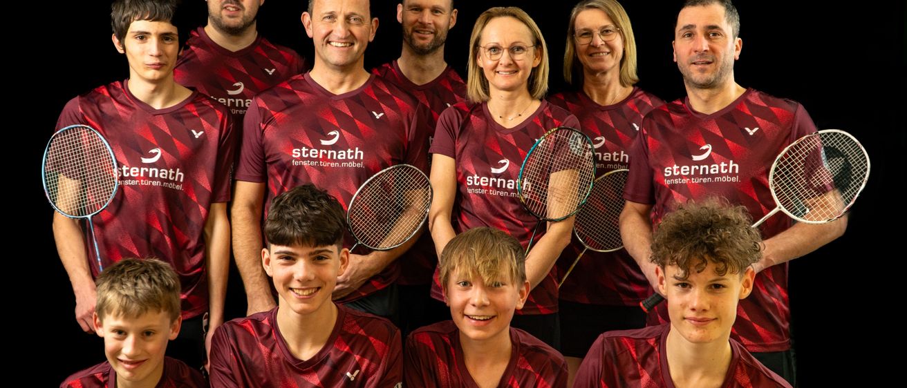 A group of people wearing red jerseys with the word 'sternath' on them are posing for a photo with rackets in their hands. They are smiling and looking at the camera.