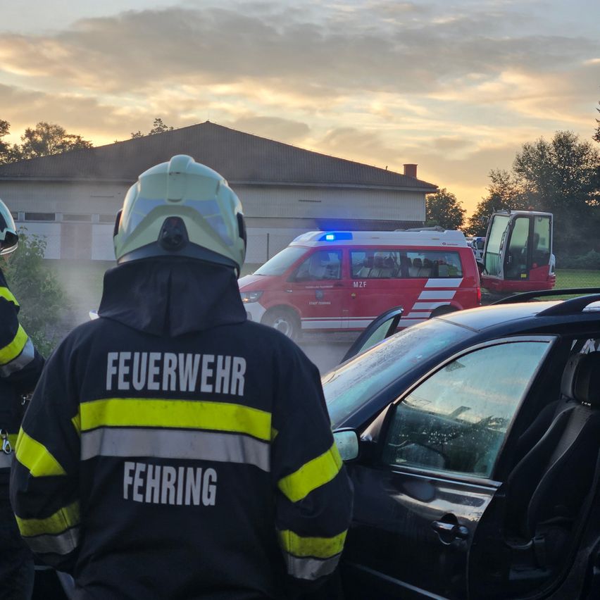 Feuerwehrleute reagieren auf einen Unfall mit einem Auto und einem Krankenwagen bei teilweise bewölktem Himmel.