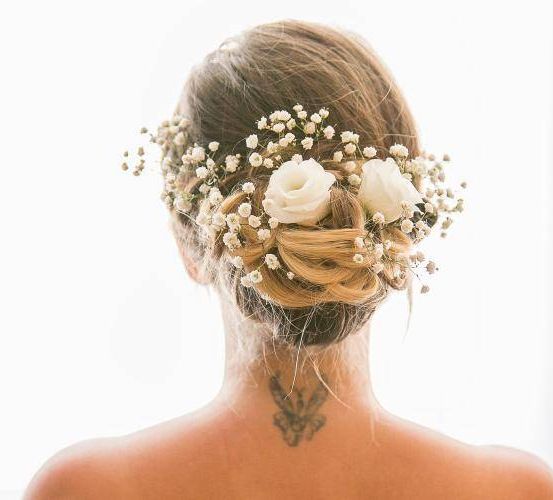 Eine Frau mit einer Blumenkrone auf dem Kopf, ihr Rücken ist sichtbar mit einem Tattoo.