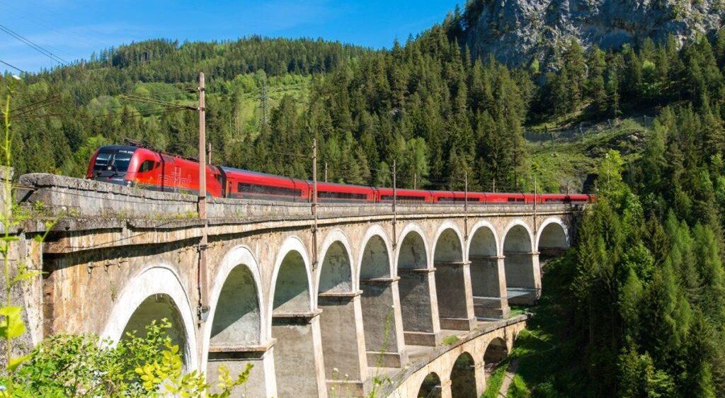 Bild enthält, Architecture, Bridge, Building, Viaduct, Train, Transportation, Vehicle, Plant, Vegetation, Arch