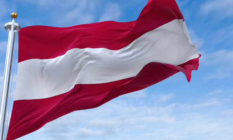The Austrian flag is waving in the wind, featuring a red and white striped design.