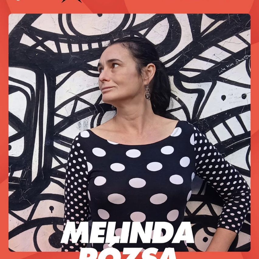Eine Frau namens Melinda Rozsa steht vor einer Wand mit Graffiti-Kunst. Sie trägt ein schwarz-weißes Polka-Dot-Oberteil. Der Hintergrund ist ein abstraktes Design in Schwarz und Weiß.