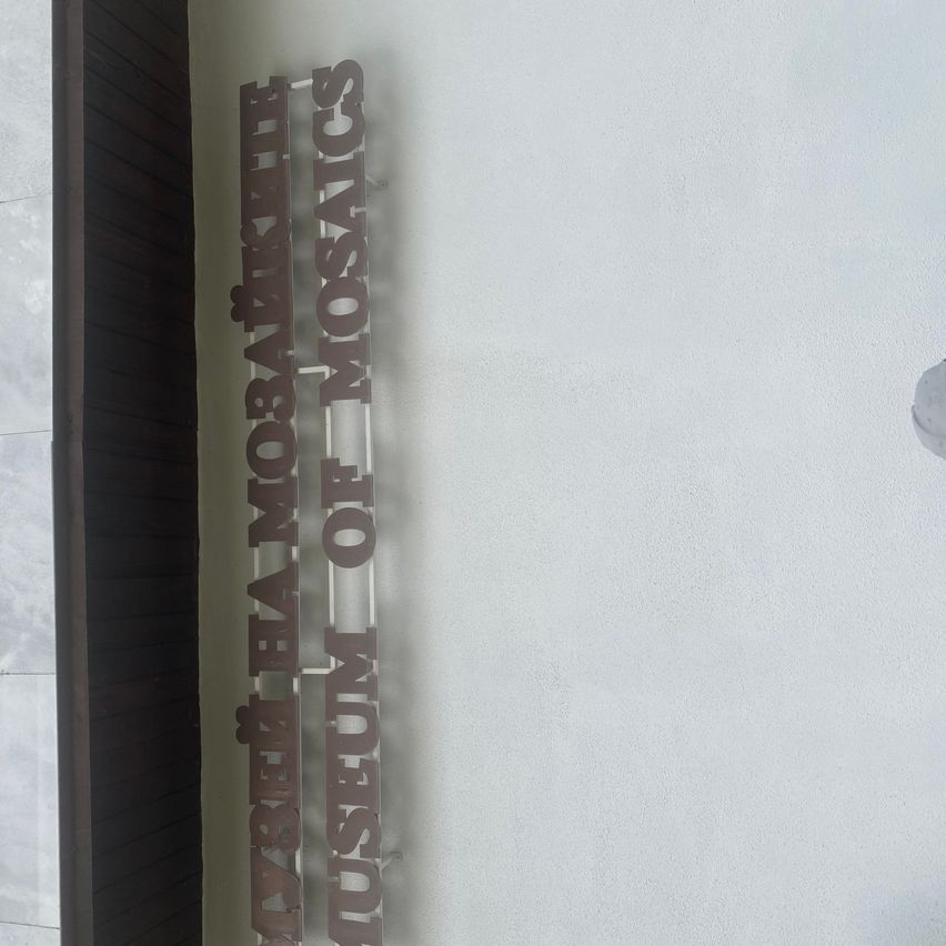 Ein an einer weißen Wand befestigtes Schild, das 'Marjeta Mosaikov Museum of Mosaics' steht.