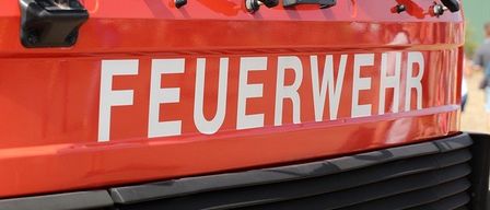 Ein roter Feuerwehrwagen mit dem Wort 'FEUERWEHR' auf der Vorderseite, einem Scheibenwischer auf der linken Seite und dem Wort 'IVECO' am unteren Teil des Stoßfängers.
