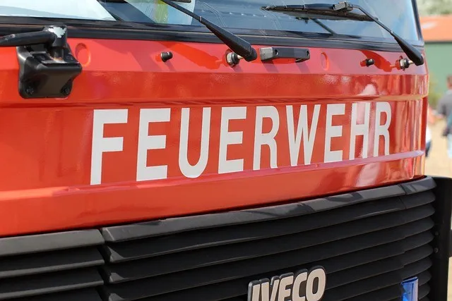 Ein roter Feuerwehrwagen mit dem Wort 'FEUERWEHR' auf der Vorderseite, einem Scheibenwischer auf der linken Seite und dem Wort 'IVECO' am unteren Teil des Stoßfängers.