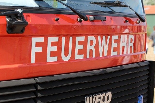 Ein roter Feuerwehrwagen mit dem Wort 'FEUERWEHR' auf der Vorderseite, einem Scheibenwischer auf der linken Seite und dem Wort 'IVECO' am unteren Teil des Stoßfängers.