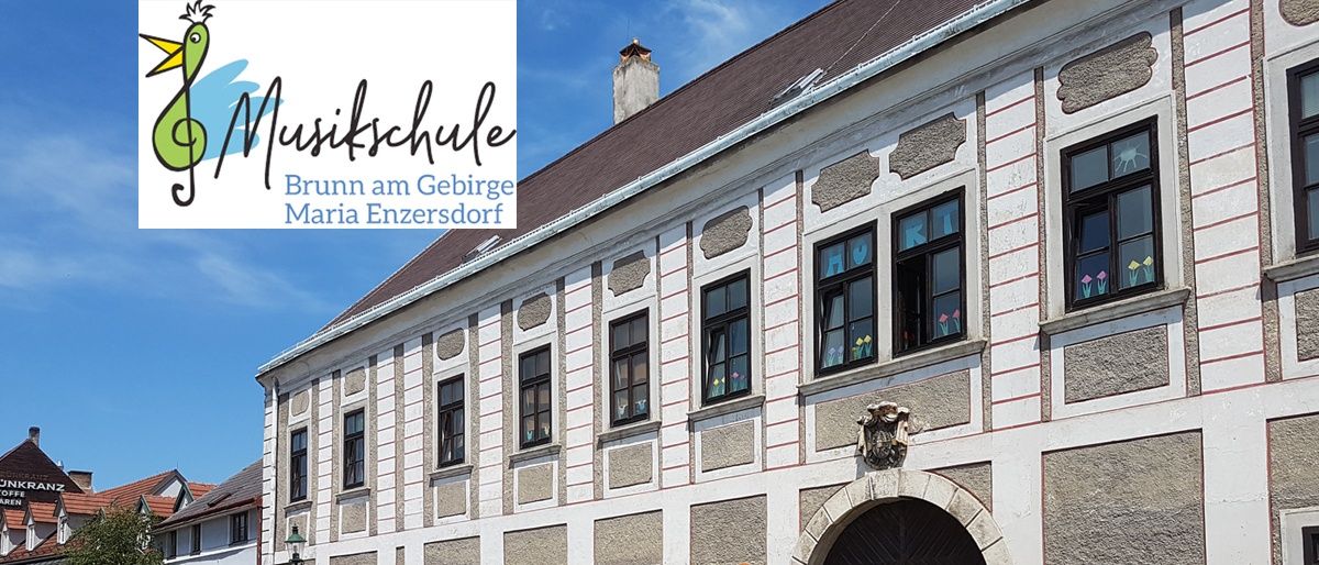 Ein Bild einer Musikschule in Maria Enzersdorf, Österreich, zeigt ein großes Gebäude mit gewölbtem Eingang, vielen Fenstern und dekorativen Elementen. Ein Auto ist davor geparkt.