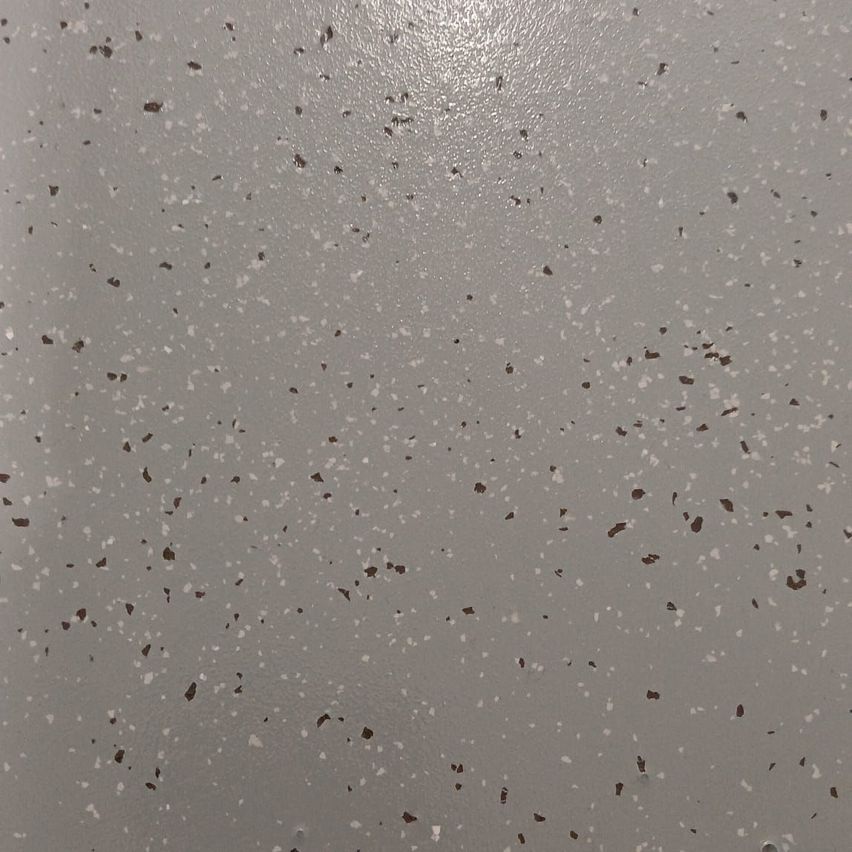 Eine Nahaufnahme einer gesprenkelten grauen Oberfläche, wahrscheinlich ein gesprenkelter Epoxidboden mit kleinen, verstreuten Partikeln in verschiedenen Grau- und Brauntönen.