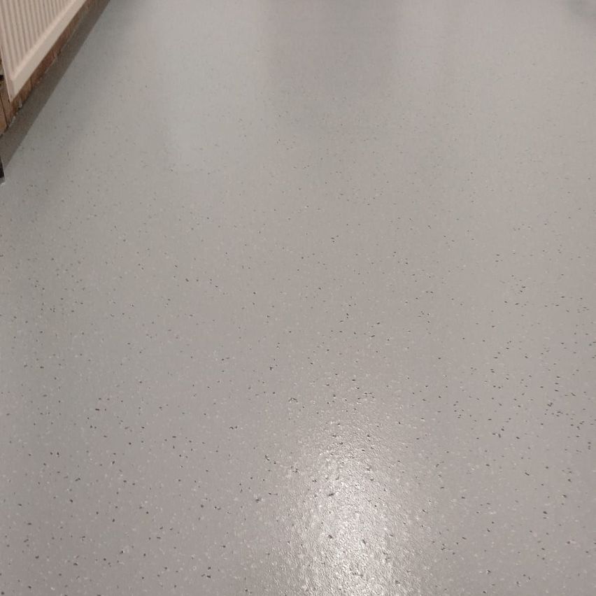 Eine Nahaufnahme eines hellgrauen, gesprenkelten Bodens mit glatter Oberfläche. Der Boden hat einige kleine Punkte, die über ihn verteilt sind.