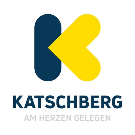Das Logo für Katschberg zeigt ein stilisiertes 'K' mit einem gelben Pfeil nach oben, vor weißem Hintergrund. Darunter steht 'KATSCHBERG AM HERZEN GELEGEN'.