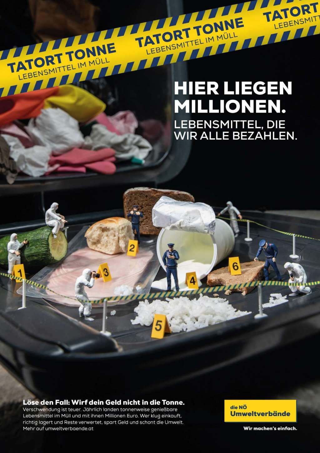 Eine Miniatur-Szene eines Verbrechens zeigt beschriftete Lebensmittel und uniformierte Beamte, was auf eine Abfallkontrolle oder eine Kontaminationsuntersuchung hindeutet. Die Szene ist von gelbem Band umgeben.