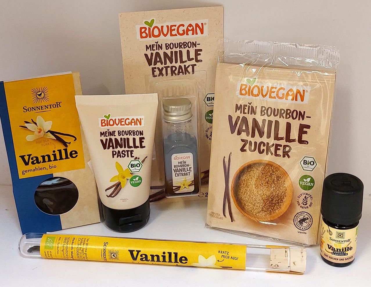 Various Biovegan products including a vanilla extract, a vanilla paste, a vanilla sugar, and a vanilla tube are displayed on a white surface.