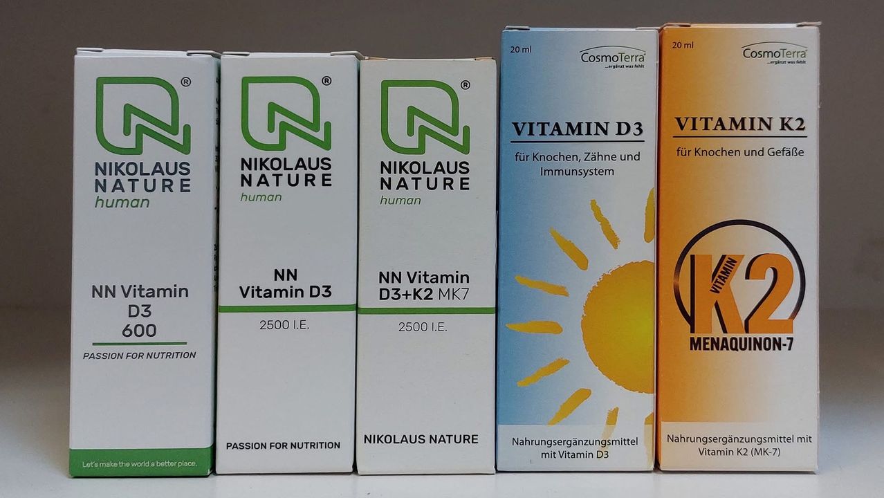 Fünf Packungen von Nahrungsergänzungsmitteln sind ausgestellt. Vier Packungen sind mit 'Nikolaus Nature' und 'NN Vitamin D3' beschriftet, während eine Packung 'Vitamin D3' trägt. Jede Packung enthält 2500 IE.