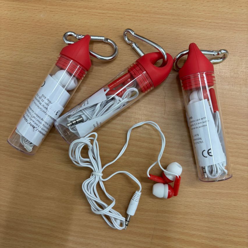 Three transparent plastic cases with red caps and earphones inside, one with a red and white earphone, placed on a wooden surface.