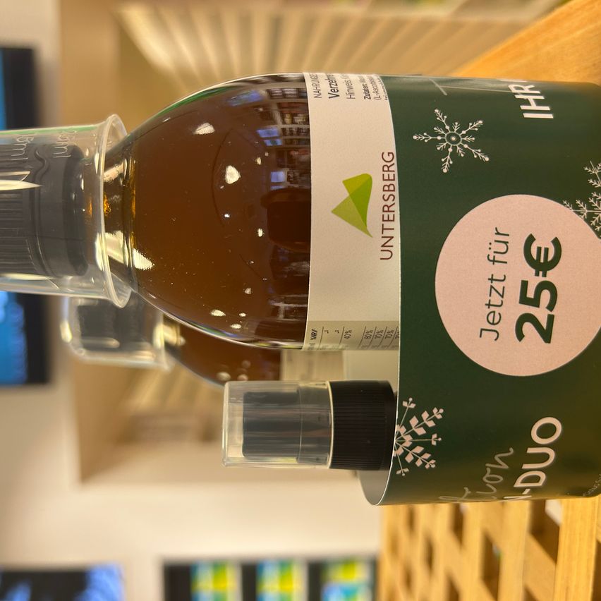 Nahaufnahme einer Flasche mit einem grünen Etikett, das ein Schneeflocken-Design und den Text 'Jetzt für 25€' zeigt. Das Etikett enthält auch den Markennamen 'Untersberg'.