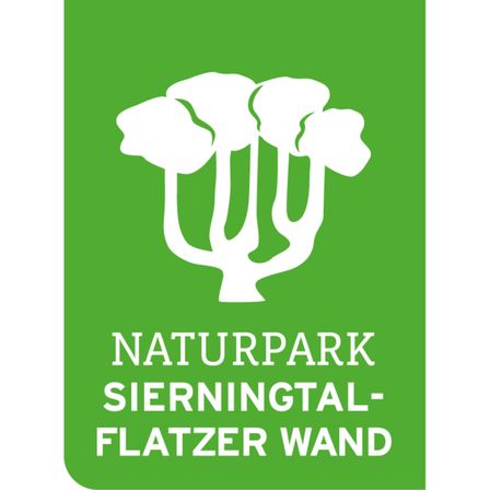 Grünes Schild mit einer weißen Baumgrafik und dem Text 'Naturpark Sierningtal-Flatzer Wand'. Der Baum hat drei Äste. Der Hintergrund ist fest grün.