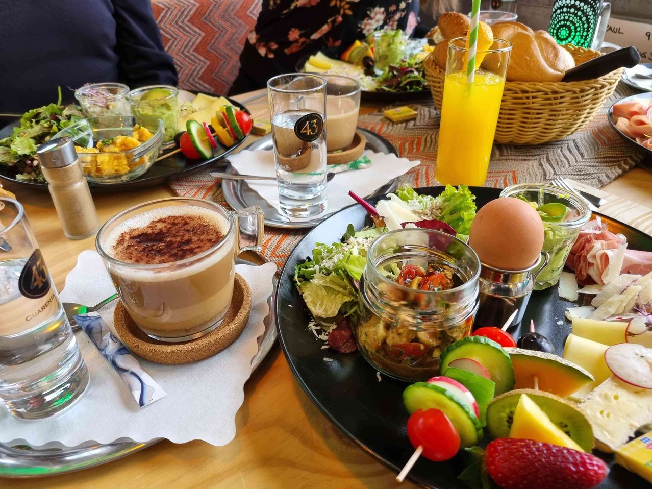 Ein Tisch mit verschiedenen Frühstücksartikeln, einschließlich Salat, einem halb gekochten Ei, einer Tasse Kaffee und Gemüse am Spieß.