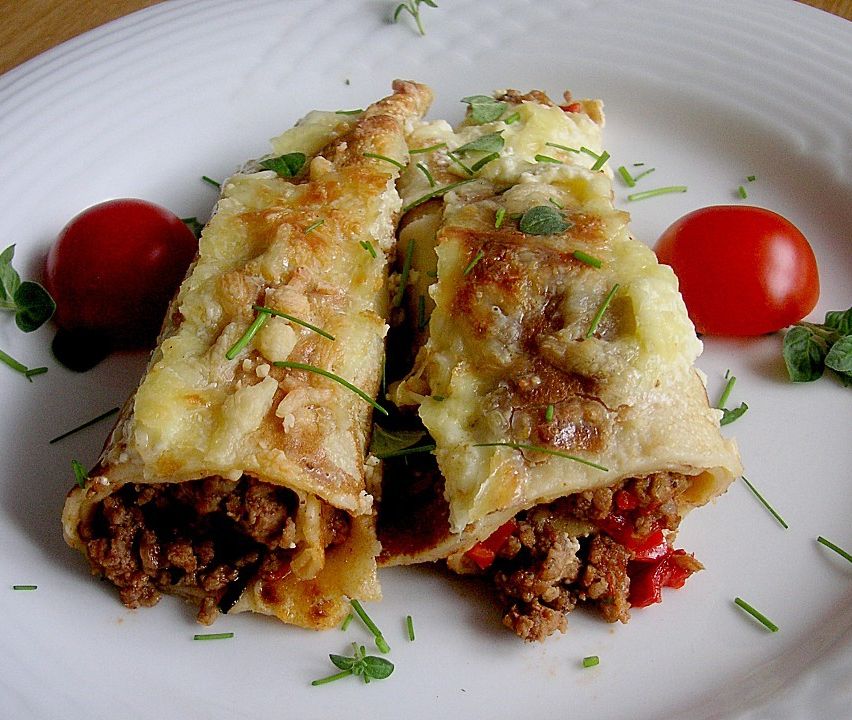 Two rolled dishes with meat and cheese, garnished with green herbs, served on a white plate with two red cherry tomatoes.
