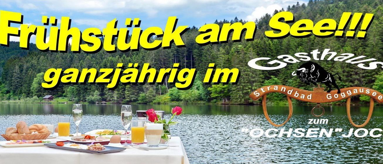 Eine Frühstücksszene am Seeufer mit einem Tisch, der am Wasser platziert ist, Blumen und einer ruhigen Waldkulisse.