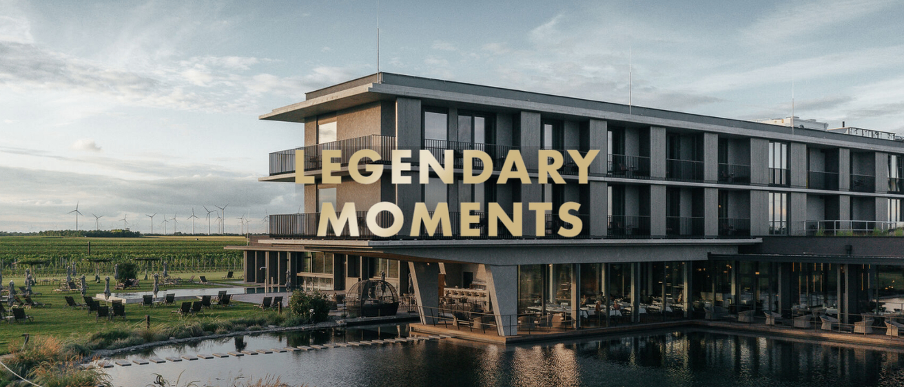Ein modernes Gebäude mit dem Schriftzug 'Legendäre Momente' in Gold über einem Restaurant mit Wasserblick.