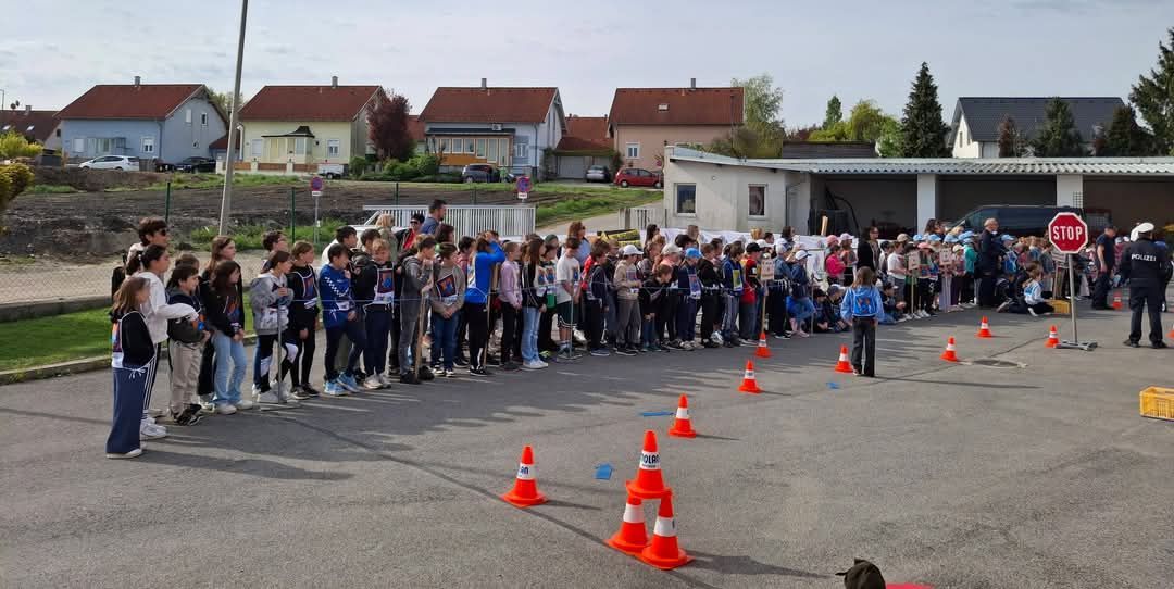 Eine Gruppe von Kindern steht in einer Reihe, möglicherweise in Erwartung einer Veranstaltung, mit Verkehrskegel, die einen Weg markieren.