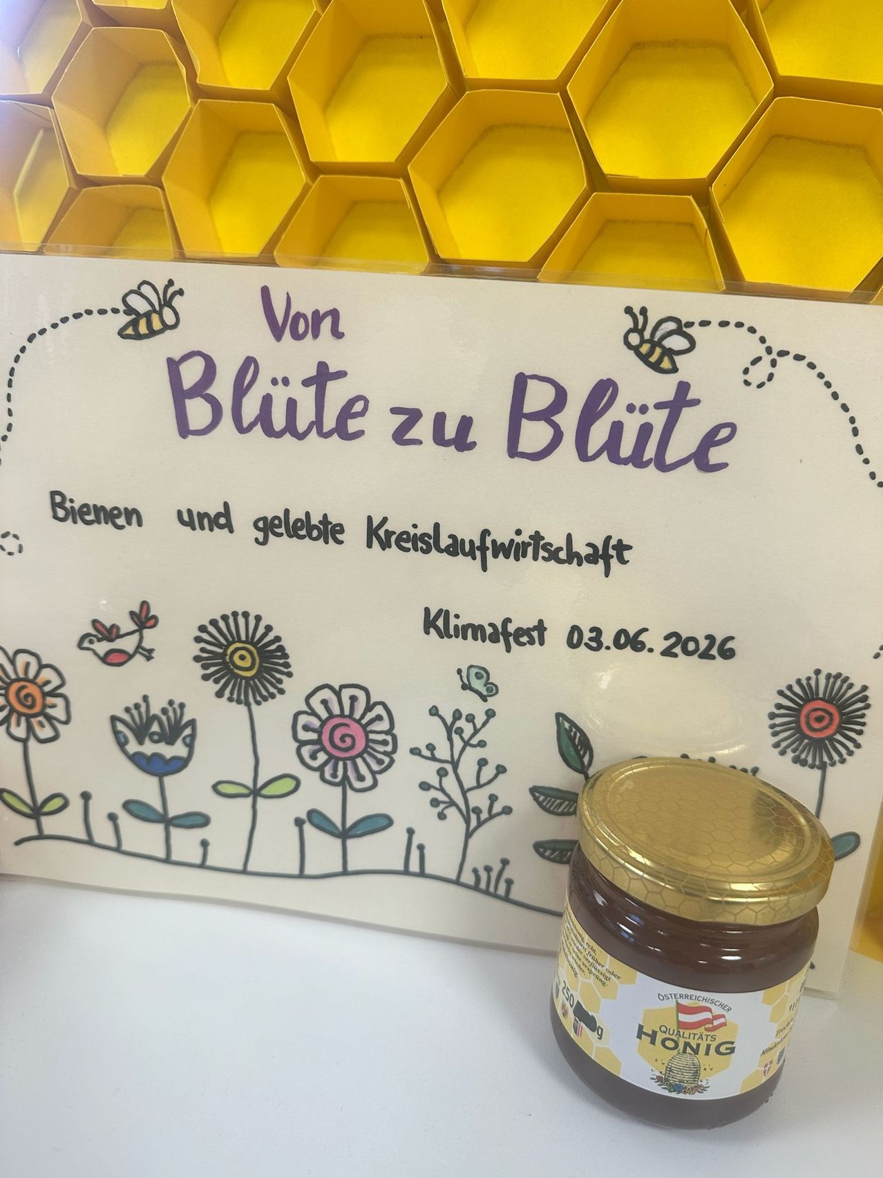 A sign reads 'From Flower to Flower, Bees and Circular Economy.' A jar of honey is nearby. The date is 03.06.2026.
