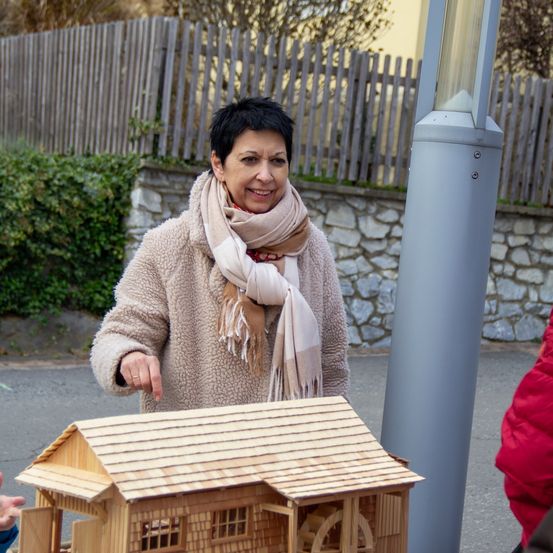 Bild enthält, Plywood, Wood, Adult, Female, Person, Woman, Sweater, Scarf, Coat, Finger