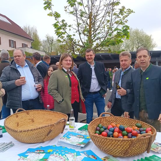 Eine Gruppe von Menschen steht hinter einem Tisch mit Weidenkörben voller Eier und Malbüchern.