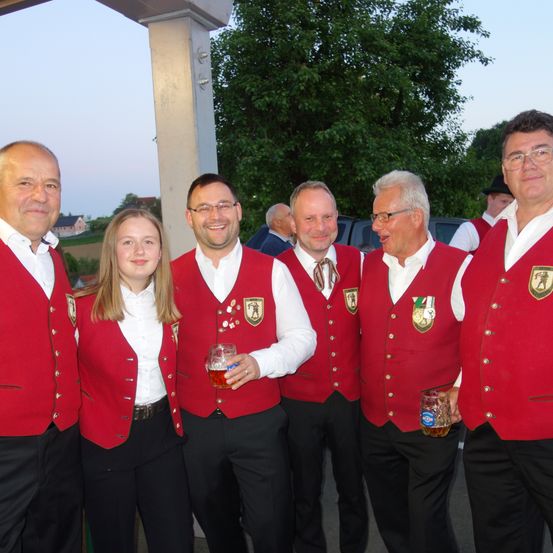 Sechs Personen posieren für ein Foto. Fünf von ihnen sind Männer, die rote Westen mit Abzeichen tragen. Die andere Person ist ein Mädchen, das eine weiße Bluse und einen schwarzen Gürtel trägt.