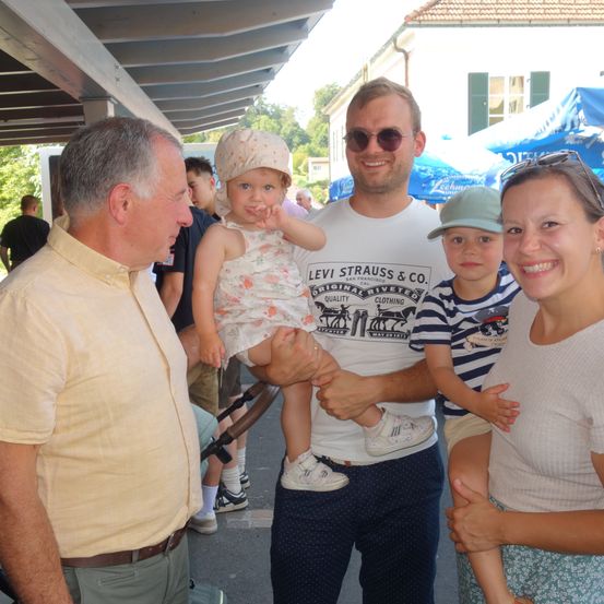 Ein Mann und eine Frau lächeln für die Kamera mit zwei Kindern, von denen eines von einem lächelnden Mann in einem Levi's-Shirt gehalten wird.