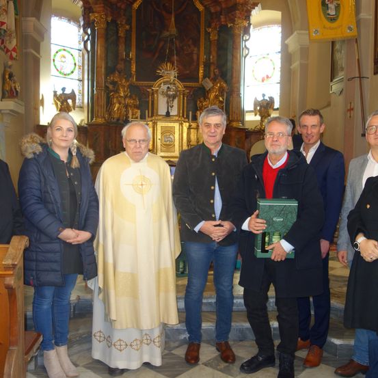 Eine Gruppe von Menschen posiert für ein Foto in einer Kirche. Ein Mann hält ein Geschenk.