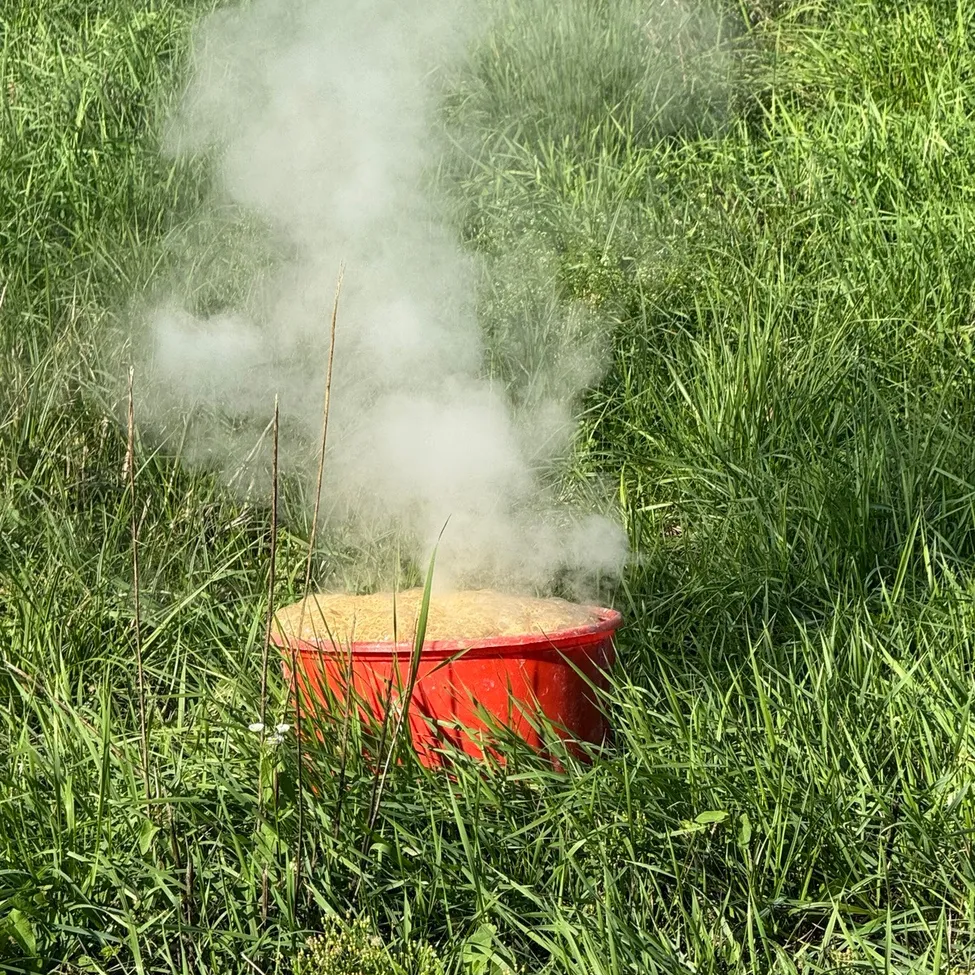 Ein roter Topf steht auf dem Gras und gibt weißen Rauch ab.