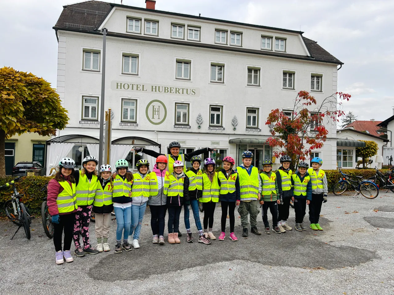 Eine Gruppe von Kindern in gelben Westen und Helmen steht vor dem Hotel Hubertus.