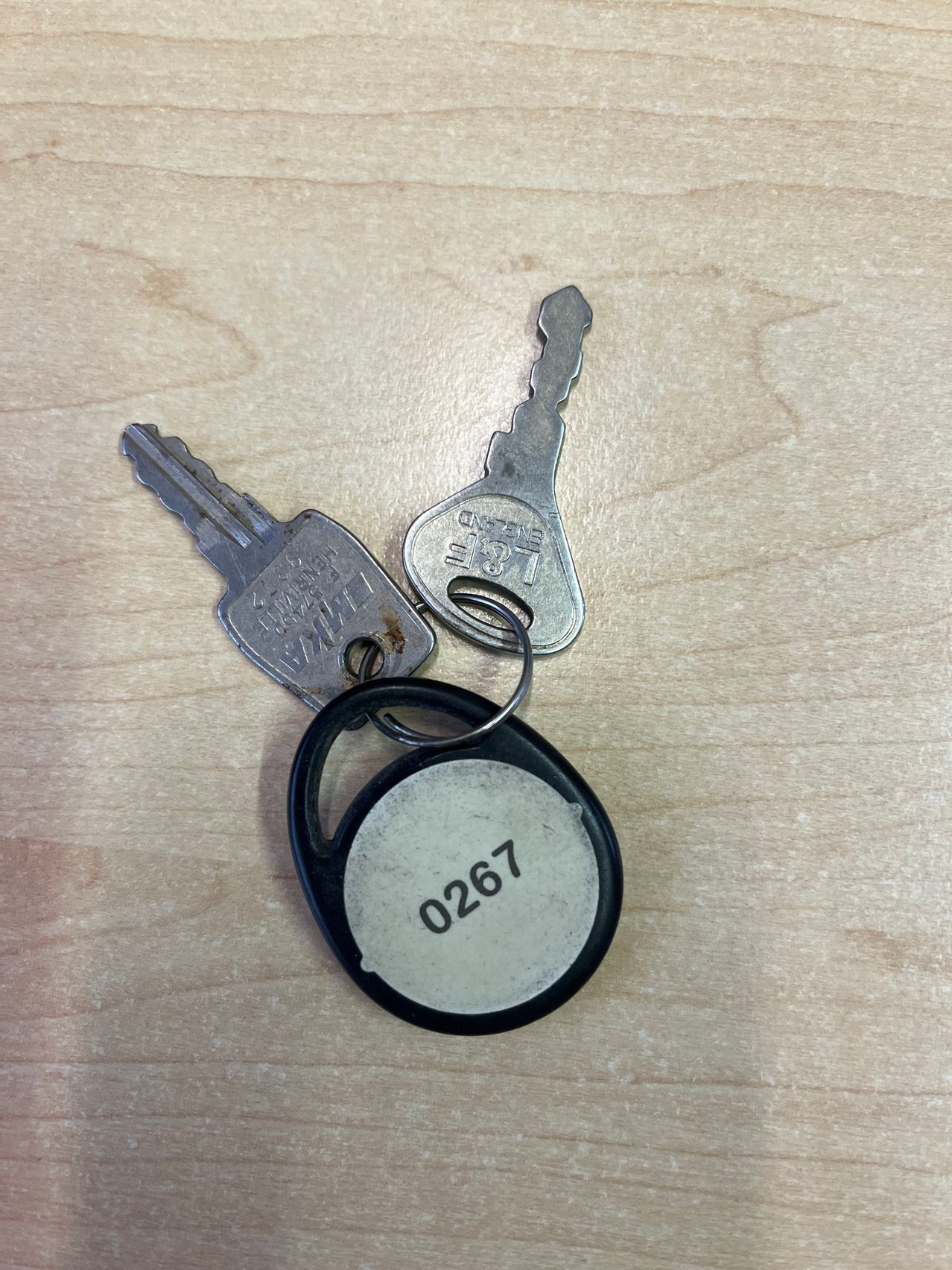 Two silver keys with keychains and a keychain with the number 0267 on it.