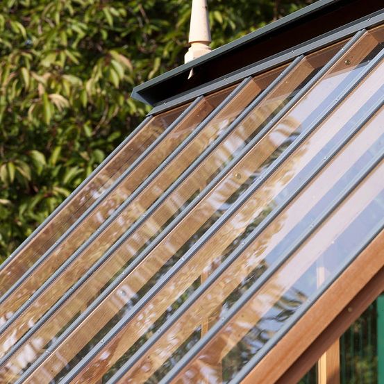 Eine Nahaufnahme des Daches eines Holzgewächshauses mit Glasscheiben.