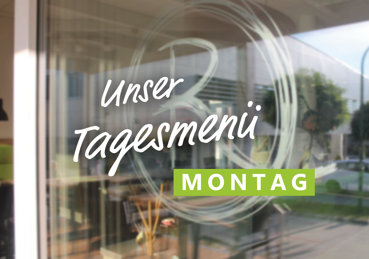 Das Bild zeigt die Tageskarte eines Restaurants für Montag. Die Karte ist auf einer Glastür mit einem verschwommenen Blick auf das Restaurantinnere zu sehen.