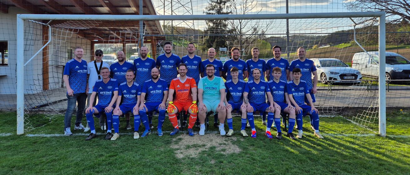 Eine Fußballmannschaft in blauen Uniformen posiert für ein Foto vor einem Tor mit Netz.