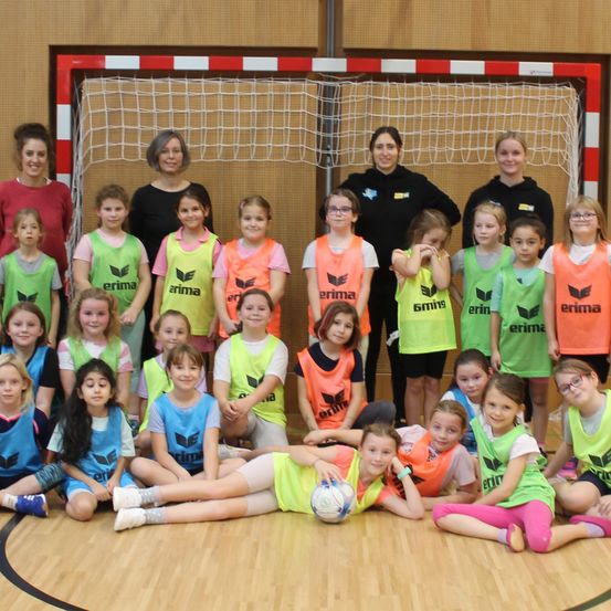 Eine Gruppe junger Mädchen in Sporttrikots mit dem Wort erima darauf posiert für ein Foto in einer Turnhalle.