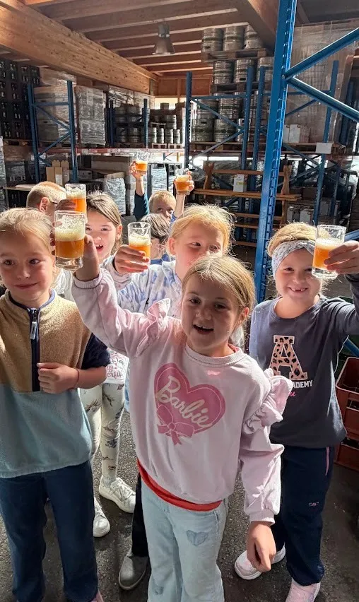 Eine Gruppe von Kindern in einem Lagerhaus hält Gläser mit Bier in der Hand.