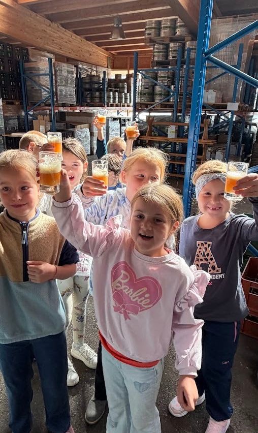 Eine Gruppe von Kindern in einem Lagerhaus hält Gläser mit Bier in der Hand.