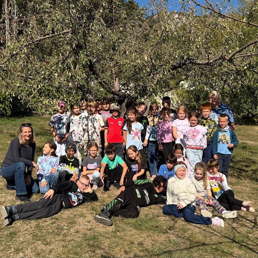 Eine Gruppe von Kindern und Erwachsenen posiert für ein Foto unter einem Baum in einem Park.