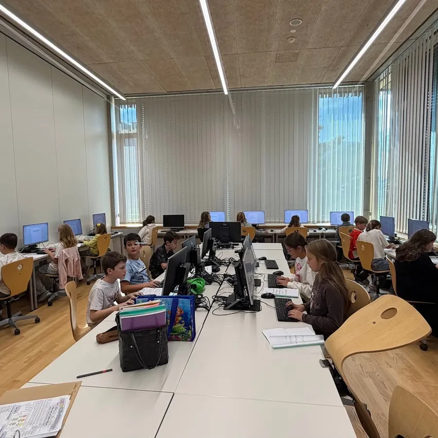 Eine Gruppe von Kindern sitzt in einem Klassenzimmer an Computern.
