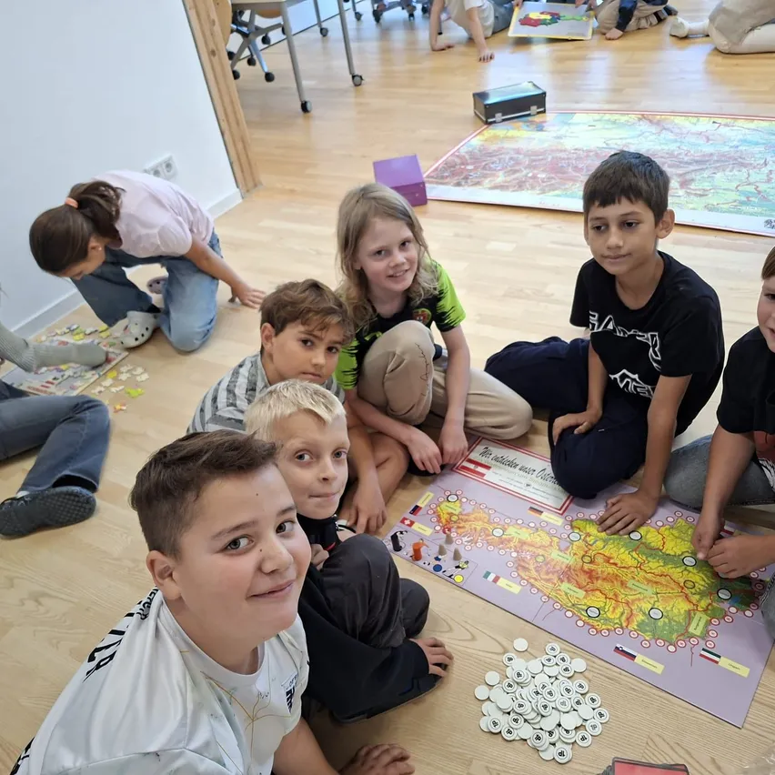 Eine Gruppe von Kindern sitzt auf dem Boden und spielt ein Brettspiel.