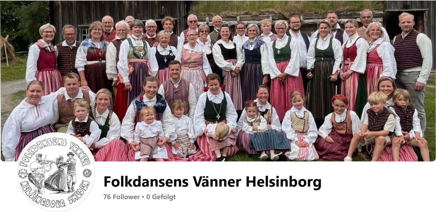 Eine Gruppe von Menschen in traditioneller Kleidung, einige mit Babys, posiert für ein Foto vor einer Holzstruktur.