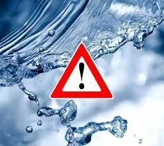 Ein rotes Dreieck mit einem Ausrufezeichen in der Mitte wird über einem spritzenden blauen Wasserhintergrund angezeigt. Das Bild warnt vor möglichen Wassergefahren.